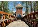 Rustic bridge with arched support beams leads to a brick building with a tower at 825 Maplewood Dr, Roswell, GA 30075