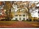 Historic home featuring white columns, a manicured lawn, and mature trees in autumn foliage at 825 Maplewood Dr, Roswell, GA 30075
