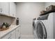 Modern laundry room with white cabinets, folding counter, and new front-load machines at 825 Maplewood Dr, Roswell, GA 30075