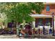 Inviting outdoor dining area with ample seating, lush trees, and a charming brick building at 825 Maplewood Dr, Roswell, GA 30075