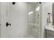 Beautiful glass shower with white marble tile, dark hardware, and river rock floor at 825 Maplewood Dr, Roswell, GA 30075