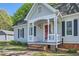 Charming single-story home with gray siding, black shutters, a red door and a covered brick porch at 3664 Bonnie Glenn Ln, Tucker, GA 30084