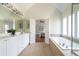 Bright bathroom featuring a soaking tub under large windows and direct access to the main bedroom at 7430 Polo Hl, Cumming, GA 30040