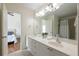 Bright bathroom featuring a double vanity, large mirror, and tiled floors, adjacent to a bedroom at 7430 Polo Hl, Cumming, GA 30040