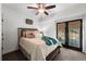 Cozy bedroom features a ceiling fan, a comfortable bed with decorative pillows, and french doors to the backyard at 7430 Polo Hl, Cumming, GA 30040