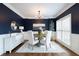 Chic dining room with navy walls, white wainscoting, chandelier, and hardwood floors at 7430 Polo Hl, Cumming, GA 30040