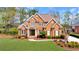 Beautiful red brick home with lush green lawn, a circular driveway, and mature landscaping at 7430 Polo Hl, Cumming, GA 30040