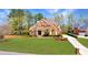 Attractive brick home with a spacious green lawn, a circular driveway, and mature trees at 7430 Polo Hl, Cumming, GA 30040
