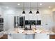 Stylish kitchen with a central island, black pendant lighting, stainless steel fridge, and ample storage space at 7430 Polo Hl, Cumming, GA 30040