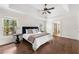 Spacious main bedroom with hardwood floors, tray ceiling, ceiling fan, and ensuite bath access at 7430 Polo Hl, Cumming, GA 30040