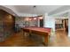 Recreation room featuring a pool table, wood floors, exposed brick, and a bar area at 7430 Polo Hl, Cumming, GA 30040