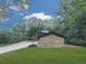 A stone facade on the side of a house complements the expansive lawn and wooded surroundings, creating a private retreat at 120 Huntcliff Pt, Atlanta, GA 30350