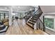 Bright foyer boasts hardwood floors, staircase with black metal railings, and view to living room with backyard access at 120 Huntcliff Pt, Atlanta, GA 30350