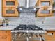 Close-up of a stainless steel gas range with custom hood and decorative backsplash at 120 Huntcliff Pt, Atlanta, GA 30350