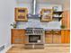 Full view of stainless steel range and hood with custom cabinets and tile backsplash at 120 Huntcliff Pt, Atlanta, GA 30350