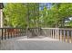 A gray stained wood deck is surrounded by lush green trees and has gray railings and stairs at 1379 Vintage Pointe Dr, Lawrenceville, GA 30044
