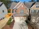 Brick-front townhome with a two-car garage and mature landscaping at 6270 Shiloh Woods Dr, Cumming, GA 30040