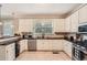 Well-lit kitchen has stainless appliances, stone backsplash, granite countertops, and white cabinets at 7155 Roswell Rd # 15, Atlanta, GA 30328