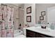 Well-lit bathroom with a bathtub, printed shower curtain, and a vanity with a sink and decorations at 15 Granville Ln, Covington, GA 30016