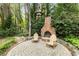 Backyard patio features brick fireplace and seating, a perfect tranquil outdoor retreat surrounded by mature trees at 259 Dartmoor Cir, Atlanta, GA 30328
