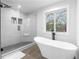 Modern bathroom features a glass enclosed shower and soaking tub under the window at 770 Waters Sw Dr, Atlanta, GA 30310
