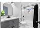 Well-lit bathroom featuring a gray vanity, white marble tile and a bathtub with black fixtures at 770 Waters Sw Dr, Atlanta, GA 30310