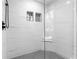Shower with sleek white tile and contrasting penny tile flooring and built-in shelving at 770 Waters Sw Dr, Atlanta, GA 30310