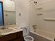Bathroom with white plastic shower over tub, white toilet, and worn vanity at 506 Carlton Dr, Palmetto, GA 30268
