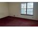 Vacant bedroom with neutral walls, red carpet, a window, and heating vent at 506 Carlton Dr, Palmetto, GA 30268