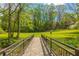 Bridge with metal railing over a creek with a view of a large grassy lawn surrounded by mature trees at 648 Channing Nw Dr, Atlanta, GA 30318