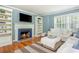 Comfortable living room featuring a tiled fireplace, built-in shelving, large windows and hardwood floors at 648 Channing Nw Dr, Atlanta, GA 30318