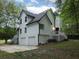 Side view of a two-story home with white siding, a black roof, an attached two-car garage, and a small deck at 7965 Tower Dr, Douglasville, GA 30134