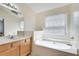 Bright bathroom features a soaking tub with natural light and a well-lit vanity at 2968 Greyhawk Ln, Cumming, GA 30040