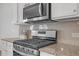 Close up of a gas range with stainless steel microwave and granite counter top at 70 Clark Lake Ln, Grayson, GA 30017