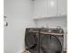 Laundry room featuring modern, front-loading washer and dryer units, storage cabinets, and white walls at 70 Clark Lake Ln, Grayson, GA 30017