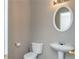 Powder room with a white pedestal sink, toilet, and round mirror at 2384 Coach Way, Jonesboro, GA 30236
