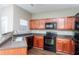 Well-lit kitchen featuring wood cabinetry, black appliances, and dark countertops at 2384 Coach Way, Jonesboro, GA 30236