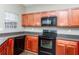 Well-lit kitchen featuring wood cabinetry, black appliances, and dark countertops at 2384 Coach Way, Jonesboro, GA 30236
