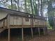 A quaint outdoor deck with wood railings is elevated, surrounded by tall trees and greenery, on a wooded lot at 4148 Silver Hill Ct, Snellville, GA 30039