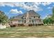 Rear exterior view of a two-story home featuring a spacious lawn, deck, and mature trees at 1405 Wilmington Way, Grayson, GA 30017