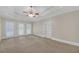 Spacious bedroom with tray ceiling, ceiling fan, carpet, and access to a private balcony at 1405 Wilmington Way, Grayson, GA 30017