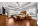 Primary bedroom with tray ceilings, hardwood floors, and shuttered windows at 4620 Westgate Dr, Cumming, GA 30040