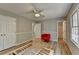 Bright bedroom with ceiling fan, a red chair, neutral paint, and updated wood-look flooring at 3081 Frankie Ln, Duluth, GA 30096