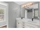 A modern bathroom featuring a double vanity, a large mirror, and a walk-in shower with glass doors at 6332 Fairoaks Pl, Douglasville, GA 30135