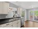 Kitchen featuring stainless steel appliances, black countertops, white cabinets, and views of the backyard at 6332 Fairoaks Pl, Douglasville, GA 30135