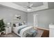 Calming main bedroom with tray ceiling, fan, ensuite bathroom, and bench seat at the foot of the bed at 6332 Fairoaks Pl, Douglasville, GA 30135
