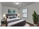 This bedroom features a bed with a gray headboard, a houseplant, and a neutral color scheme at 13030 Dartmore Ave, Alpharetta, GA 30005