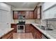 Close-up of kitchen showing stainless steel oven, granite counters, and plentiful dark wood cabinets at 13030 Dartmore Ave, Alpharetta, GA 30005