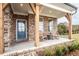 Charming brick front porch featuring wooden columns, rocking chairs, and a welcoming blue front door at 5109 Hillside Haven Dr, Powder Springs, GA 30127
