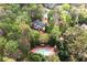 Aerial view of a home with a tennis court, surrounded by mature trees and lush greenery at 1886 Chedworth Ct, Stone Mountain, GA 30087